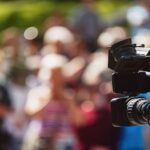 A videocamera facing a large crowd.