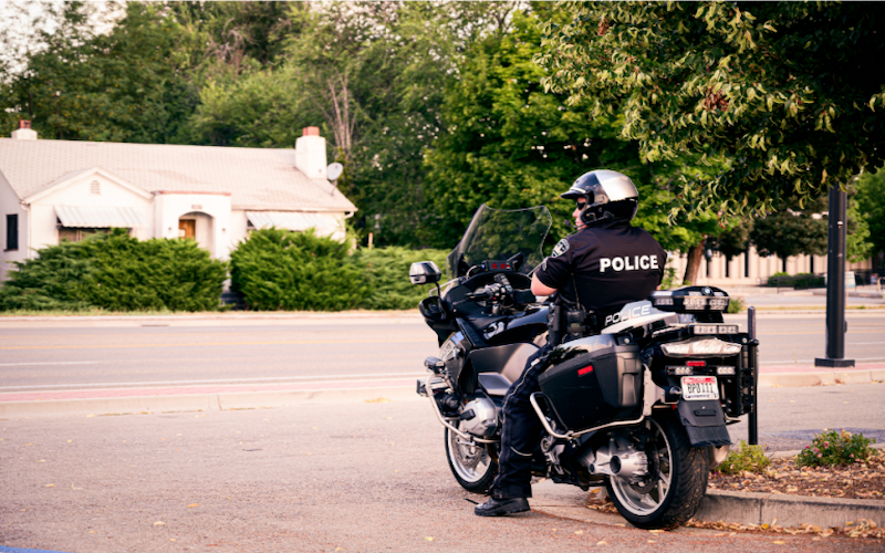 Image of police officer on a motorcycle that is sitting stationary on a street.