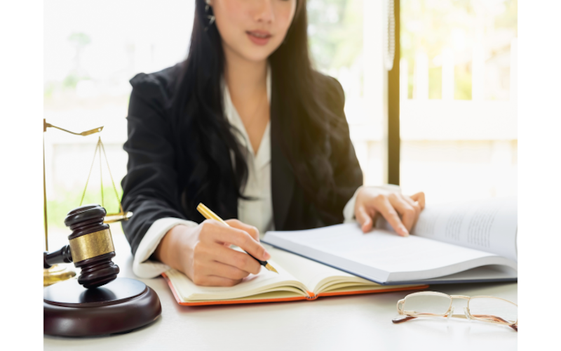 Image of woman sitting at a desk, writing notes on a notebook.